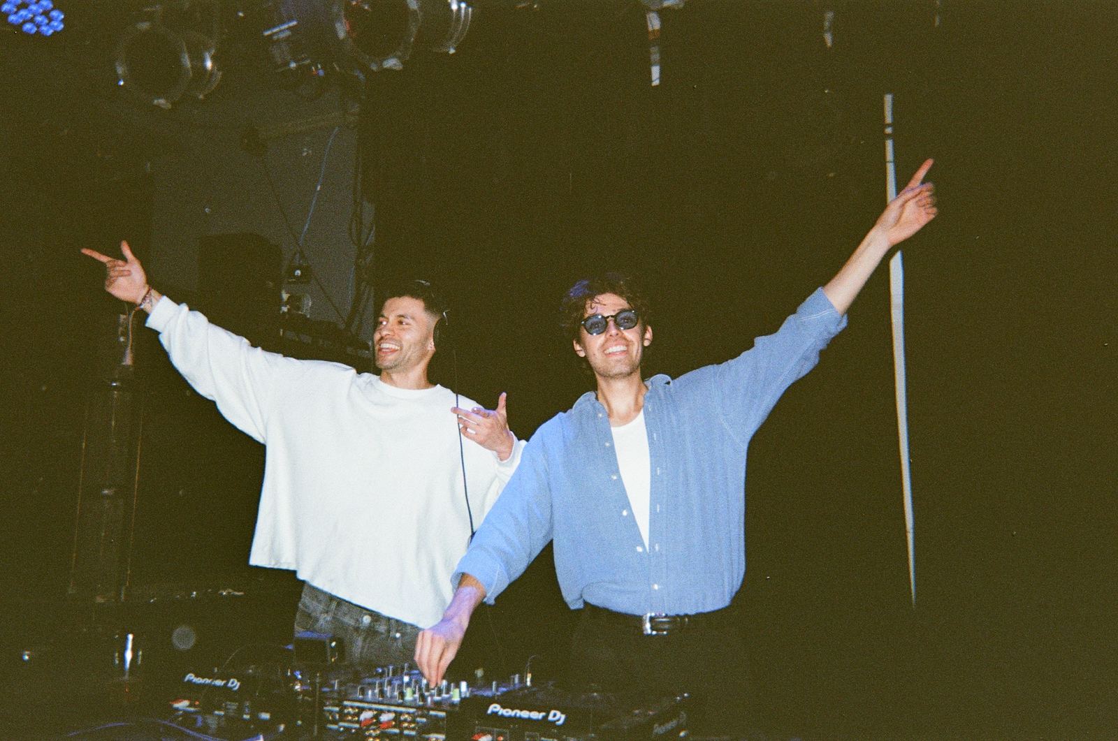 The two members of tradeoff behind the decks, arms spread wide